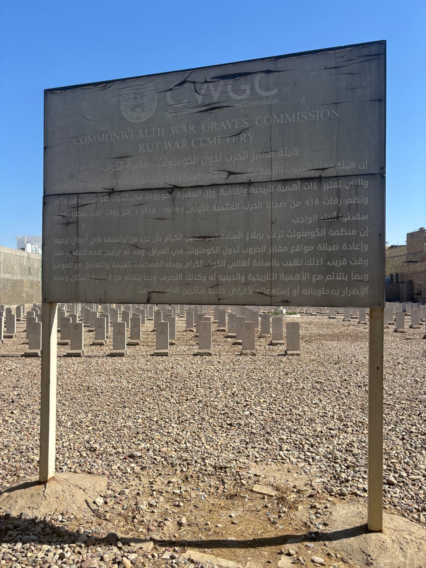 The CWGC signage at the entrance, the paint peeling and the bilingual text almost illegible, evidence that the site has not been professionally maintained since the renovation.