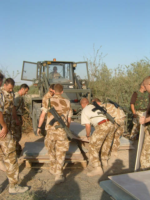 British Army personnel lifting a memorial panel for removal.