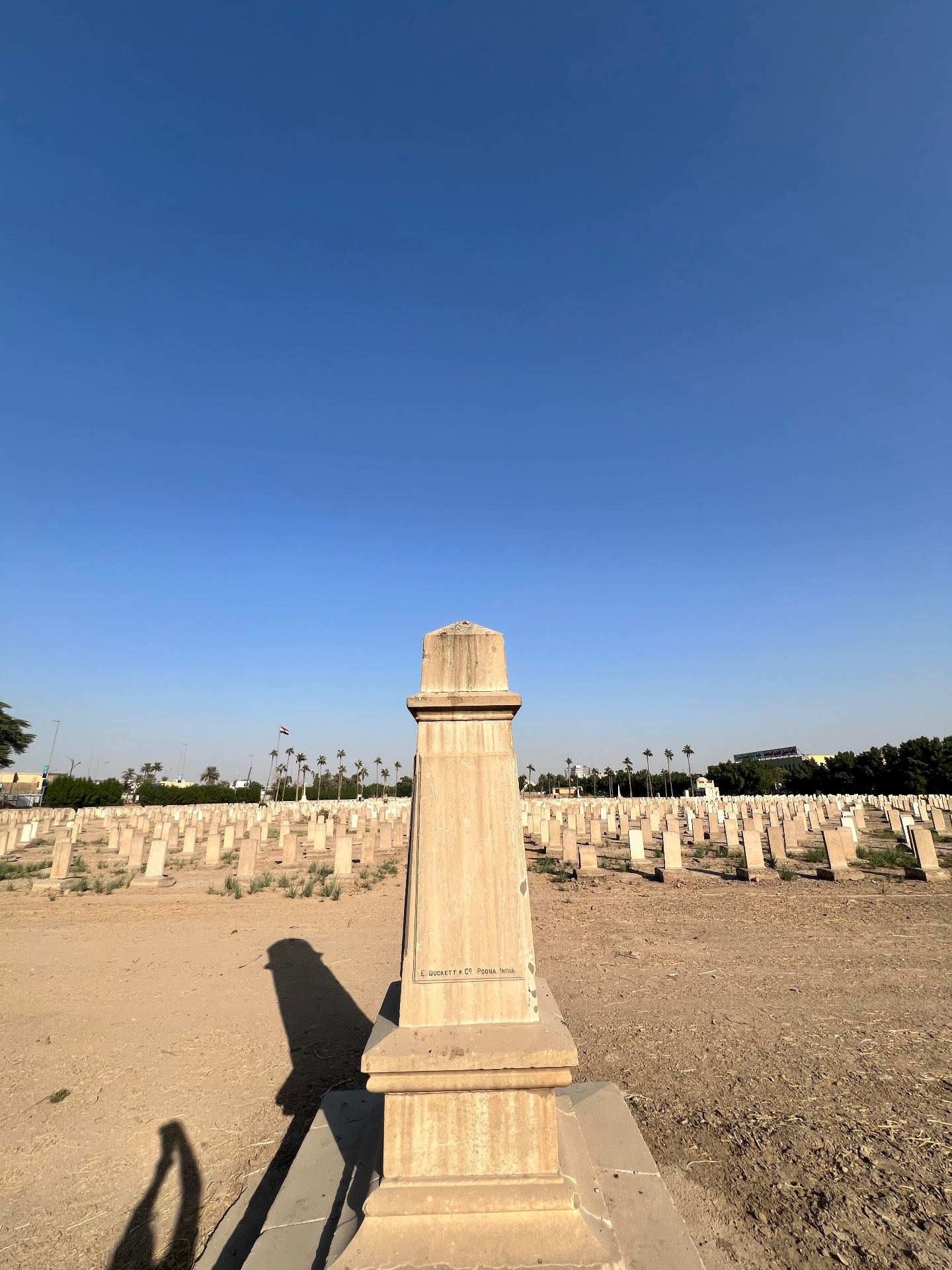 The 6th Battalion Loyal North Lancashire Regiment memorial obelisk standing among the rows of headstones at Baghdad Northgate, originally erected on the banks of the Diyala River and brought into the cemetery in 1947. The maker's mark at the base reads "E. Duckett & Co., Poona, India."